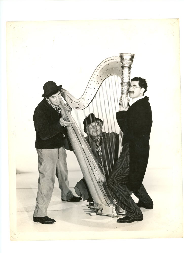 Item #000012475 Promotional Still Photograph of the Marx Brothers Gathered around a Harp. Marx Brothers, Harpo Marx, Groucho Marx, Film History, Vaudeville, Film Promotion / Advertising.